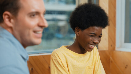 Smiling african boy sitting in circle while listening diverse friend sharing idea in group therapy...