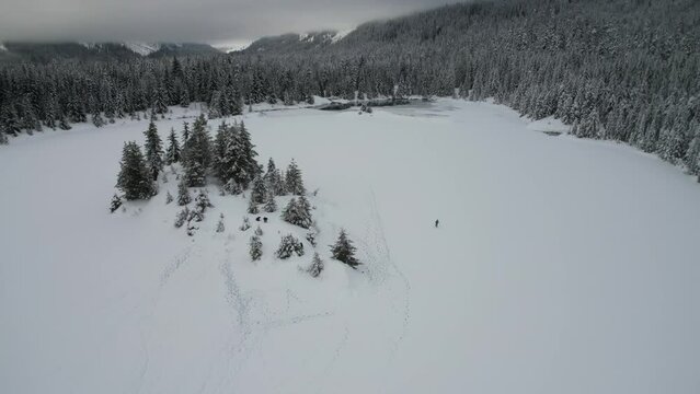 Adventurous Hikers Traversing a Vast Snowy Landscape with Footprints Etched in Snow, Aerial View of a Winter Trek