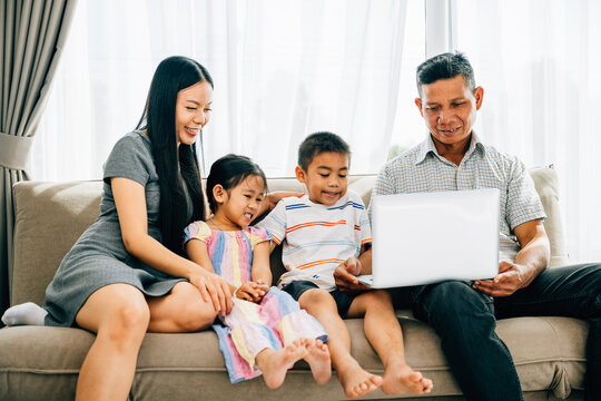A joyful family enjoys a laptop on a cozy sofa parents and little ones engaged in online activities. This image reflects familial togetherness happiness and the joy of shared technology.