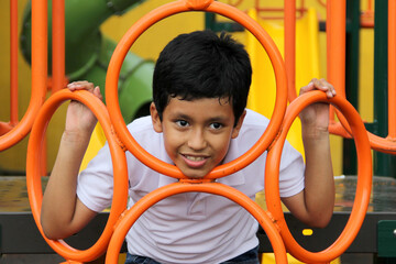 9-year-old dark-skinned Latino boy plays in a playground as a physical activity living in poverty as therapy for ADHD