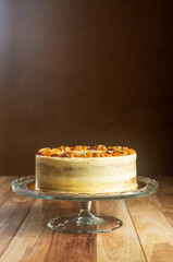 A whole carrot cake with cream cheese frosting on a glass cake stand