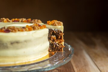 close up sliced carrot cake with cream cheese frosting on a glass cake stand