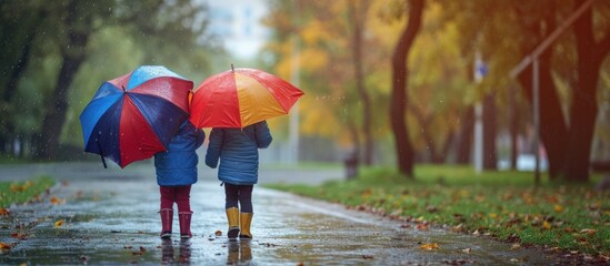 Children playing with umbrella in park on rainy day - obrazy, fototapety, plakaty