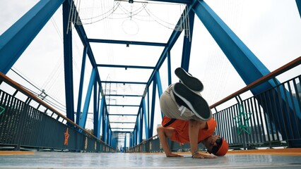 Professional break dancer perform street dance footstep at bridge. Asian hipster wear headphone...