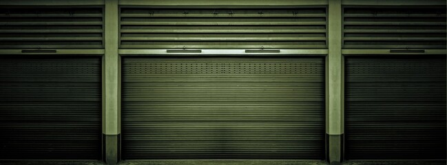 Rusty old weathered dark green steel shutter door of warehouse, storage or storefront for metal door background and textured.