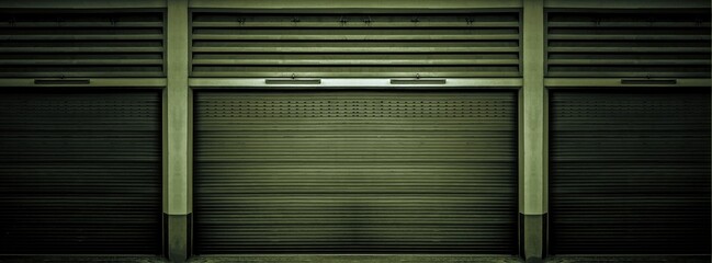 Rusty old weathered dark green steel shutter door of warehouse, storage or storefront for metal door background and textured.
