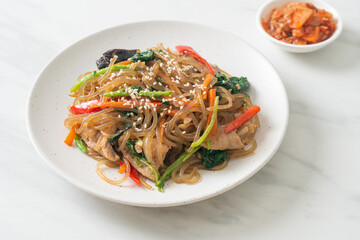 japchae or stir-fried Korean vermicelli noodles with vegetables and pork topped with white sesame