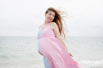 Fototapeta na wymiar Happy Caucasian woman with long hair on the beach. Pregnancy near the ocean. happy pregnancy concept. 