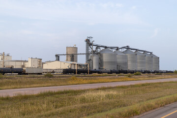 Fototapeta na wymiar Industrial Grain Silo Complex with Train Loading Facility at Sunset