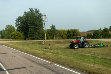 Farm Tractor with Attachment Working Near Roadside in Rural Area