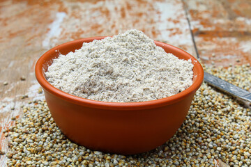 Pearl millet powder in a bowl on wooden background side view 