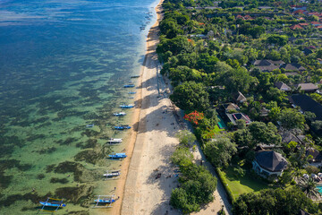 Overhead view of traditional boats moored off a tropical beach with fringing coral reef in Sanur