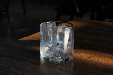 Empty glass with ice on wooden table with copy space.