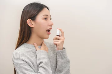 Poster Health care treatment sore throat concept, sick pain asian young woman have cough symptom holding medicine bottle, using spray in mouth to protect disease from bacteria, illness from virus infection. © KMPZZZ
