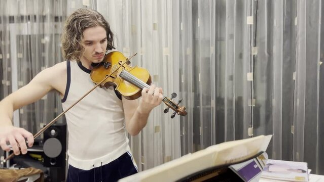 Young handsome man playing violin at home
