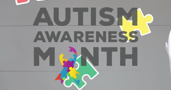 Animation of autism awareness month text and puzzle pieces on grey background