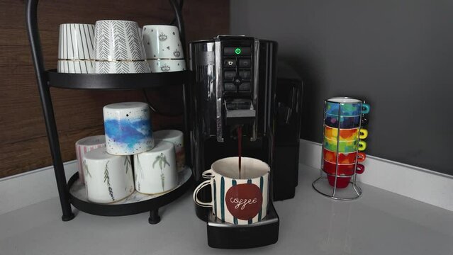 lose-up of a coffee machine placed on a kitchen bench is pouring coffee into a mug with the description of Hello on it.
