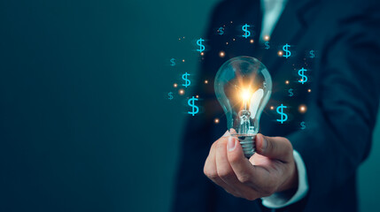 Businessman holding a light bulb with glowing money dollar signs, representing profitable business...
