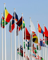 Group of flags of many different nations against blue sky