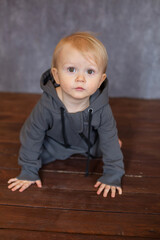 Naklejka premium A handsome little boy in a grey jumpsuit at home