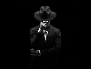 Man on a black background in a suit and hat
