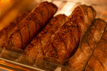 Appetizing fresh black baguettes on the counter in a store. Delicious traditional breakfast pastries. Close-up.