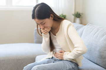Unhappy pregnant asian young woman, pain girl suffering from nausea, having vomit feeling sick covering mouth, touching belly having problem throwing up from food poisoning, lady with morning sickness - obrazy, fototapety, plakaty