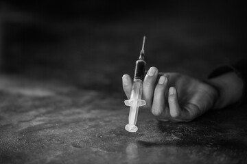 Young woman  hand holding a syringe and drug overdose,The concept of crime and drug addiction. 26 June, International Day Against Drug abuse. - obrazy, fototapety, plakaty