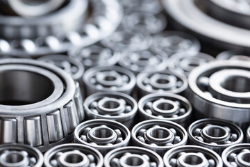 Close-up background of roller and ball radial bearings laid on the surface. Metal bearings for large machinery, equipment and various types of mechanical engineering with copy space - obrazy, fototapety, plakaty