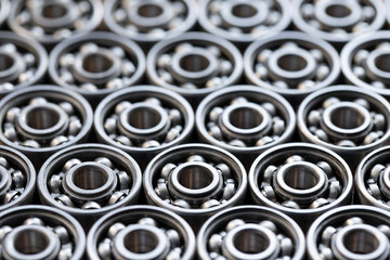 Metal radial bearings laid in a row on a surface close-up. Background of many bearing mechanisms for technology, mechanical engineering and production equipment with copy space.