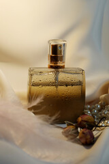 Blank perfume bottle with gold and marble cup in front of a brunch of cherry blossom. Photography in beige tones