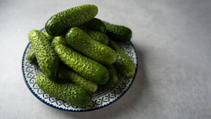 Fresh cucumbers on a plate, light gray stone background, banner, space for text