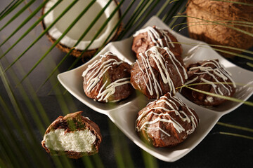 Chocolate profiteroles, eclairs, with coconut cream on a dark background