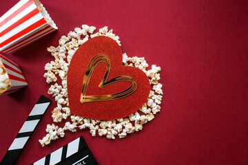 A banner for the film industry. A romantic movie date. A movie camera, 3D glasses, popcorn and a popcorn heart on a red background. The film will premiere on Valentine's Day.