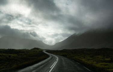 Einsame Straße mit Bergen im Hintergrund bei bedrückend, dunkler Stimmung.