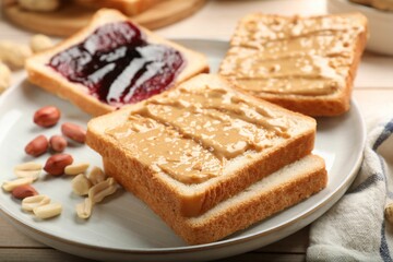 Delicious toasts with peanut butter, jam and nuts on table, closeup