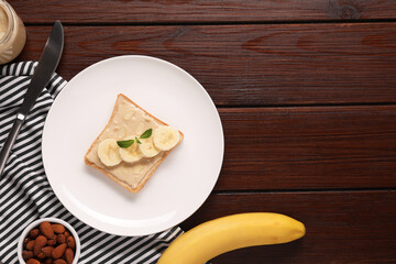 Toast with tasty nut butter, banana slices and almond flakes on wooden table, flat lay. Space for text