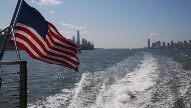 View from sailing ship to water foam, US flag and New York city