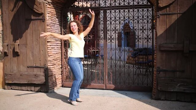 Smiling woman dances at street with Arabic wrought iron gates