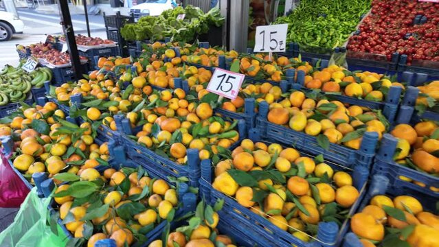 a greengrocery displays fresh fruits and vegetables such as mandarin, banana, tomato, eggplant, orange, paprika and persimmon in winter.