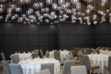 The table setting in restaurant. Decorated holiday table. Round lamps hanging from ceiling in restaurant. Lamps decorated on the ceiling in restaurant. Celebrations in a restaurant. Original luxury de