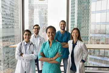Multiethnic medical staff of hospital posing in office hall with large window and city view. Happy...