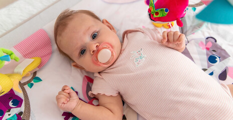 a baby plays with hanging toys on a play mat. a child, a baby plays at home