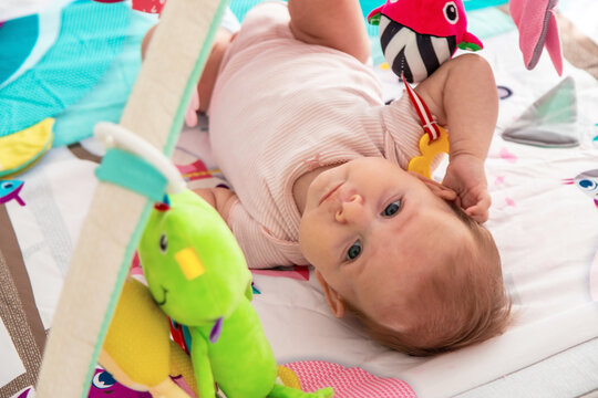 a baby plays with hanging toys on a play mat. a child, a baby plays at home