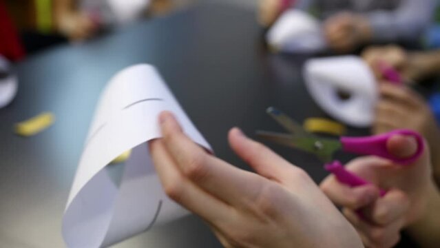 The girl is going to cut the paper on a line to get a Mobius strip