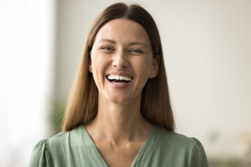 Cheerful beautiful young European woman head shot portrait. Happy pretty female Caucasian model looking at camera with toothy smile, laughing, showing healthy white teeth