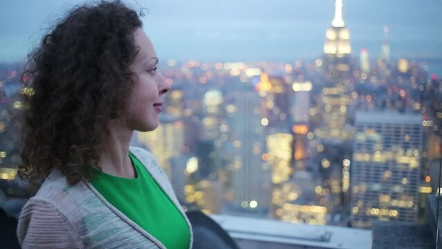 Woman smiles and stands on observation deck on roof of tall building