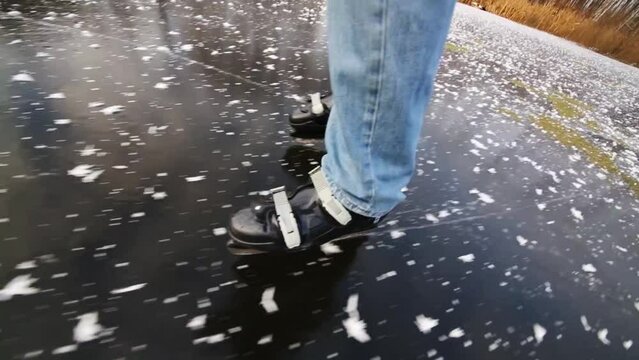 Legs of man in jeans skating on frozen lake among trees