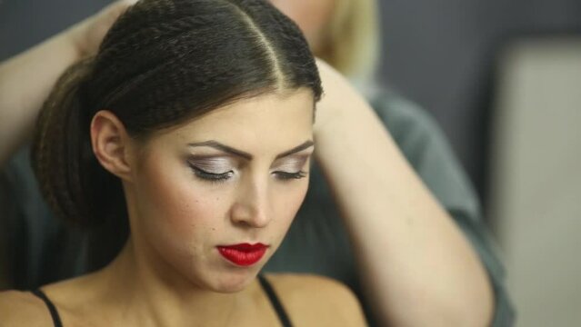 Visagiste makes hairdress to girl model in studio.