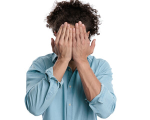 closeup of unhappy casual man covering his face